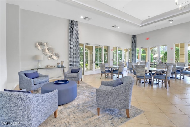 interior space with a tray ceiling, a towering ceiling, and french doors