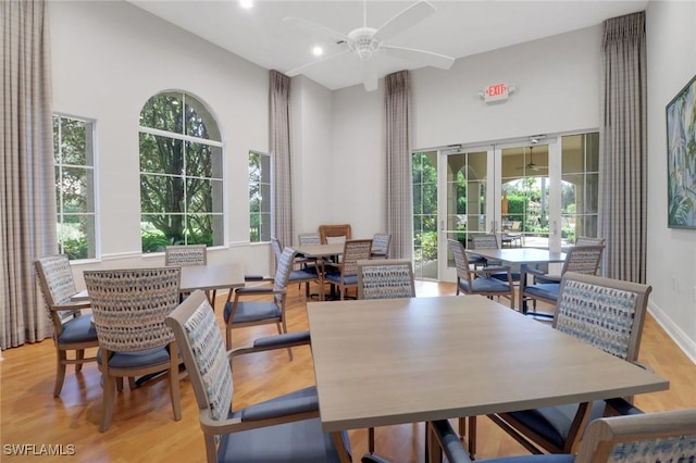 dining area with ceiling fan, light hardwood / wood-style flooring, and a towering ceiling