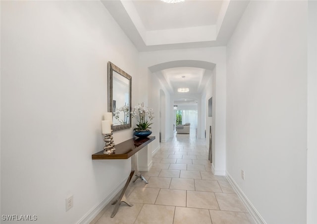 corridor with a raised ceiling and light tile patterned floors