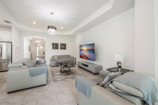 living room featuring a raised ceiling, light tile patterned flooring, and a notable chandelier