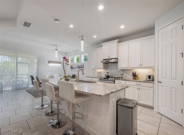 kitchen featuring stainless steel electric range oven, pendant lighting, an island with sink, sink, and white cabinets