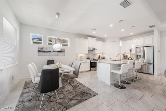 dining space with light tile patterned flooring, sink, and a chandelier