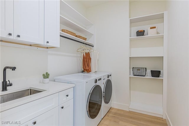 laundry room featuring cabinets, washer and dryer, sink, and light hardwood / wood-style floors