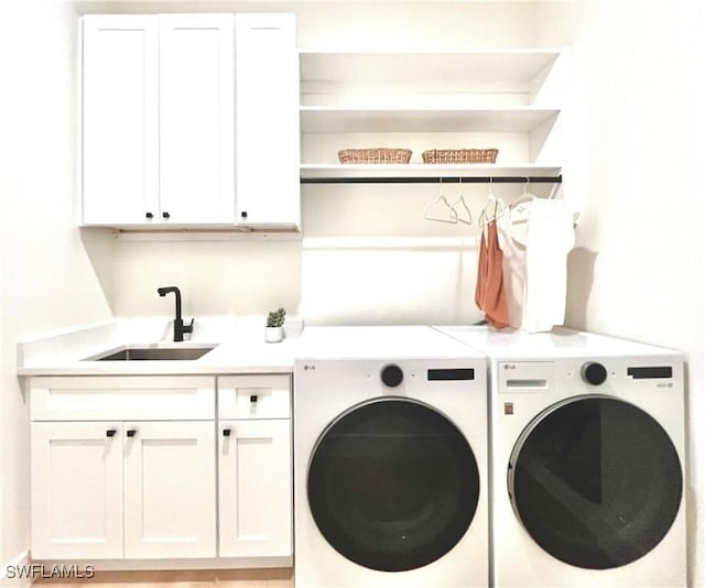 laundry area featuring separate washer and dryer, sink, and cabinets