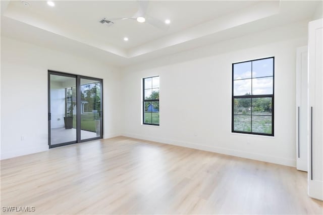 spare room with light hardwood / wood-style flooring, a raised ceiling, and ceiling fan