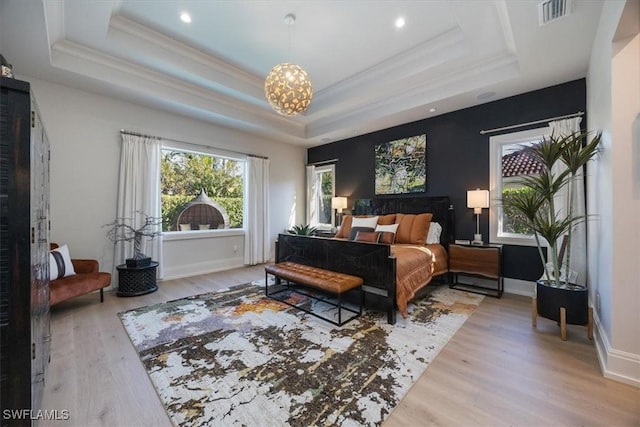 bedroom featuring a raised ceiling, wood finished floors, baseboards, and visible vents