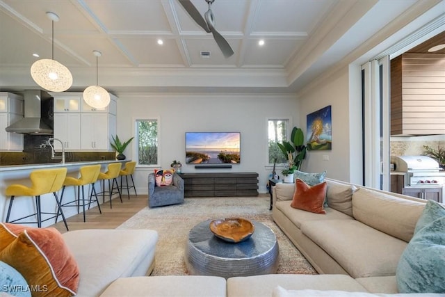 living area featuring crown molding, recessed lighting, a ceiling fan, light wood-type flooring, and coffered ceiling