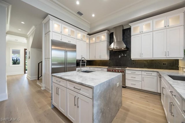kitchen with stainless steel stove, visible vents, crown molding, a sink, and wall chimney range hood