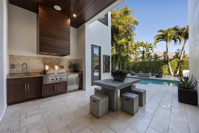 view of patio with a fenced in pool, a sink, an outdoor kitchen, and area for grilling