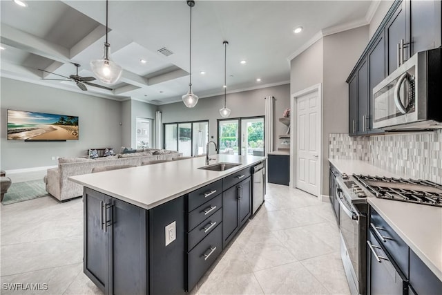 kitchen with sink, appliances with stainless steel finishes, a kitchen island with sink, backsplash, and decorative light fixtures