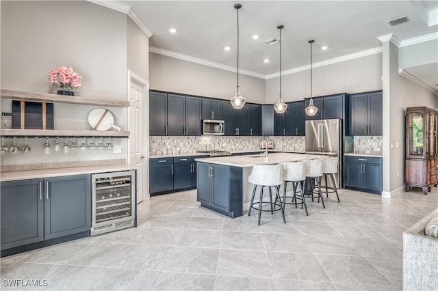 kitchen with wine cooler, blue cabinets, a breakfast bar, sink, and appliances with stainless steel finishes