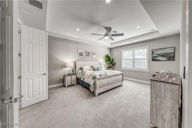 carpeted bedroom featuring a tray ceiling and ceiling fan