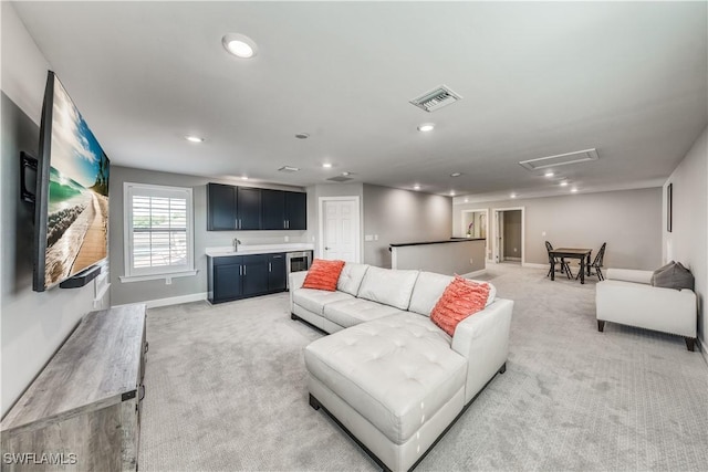 living room featuring light colored carpet and indoor wet bar