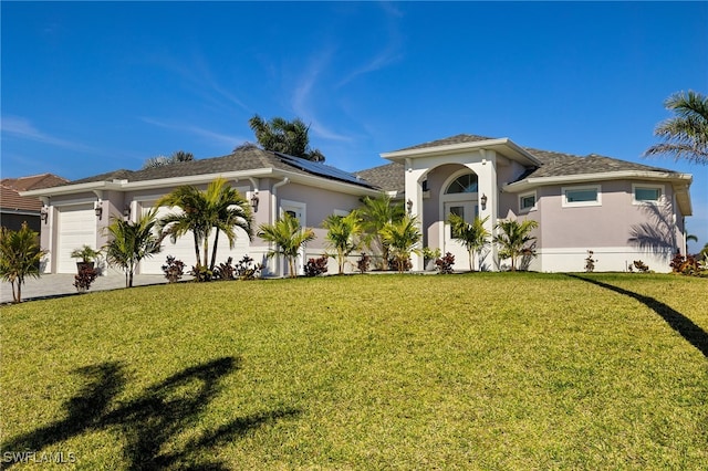 view of front facade featuring a garage, a front lawn, and solar panels