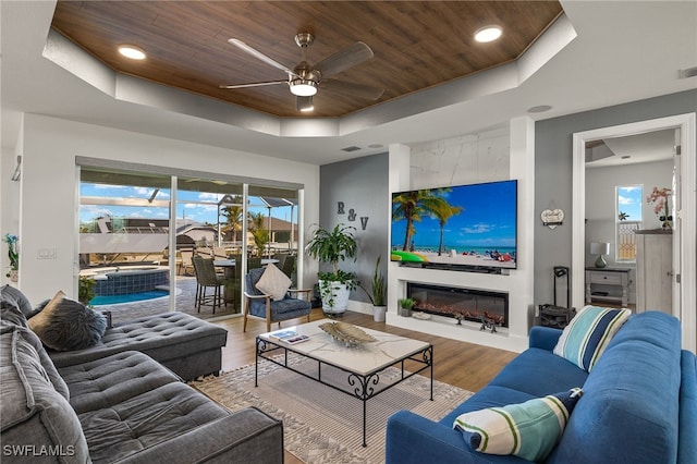 living room with wood-type flooring, a wealth of natural light, wooden ceiling, and a tray ceiling