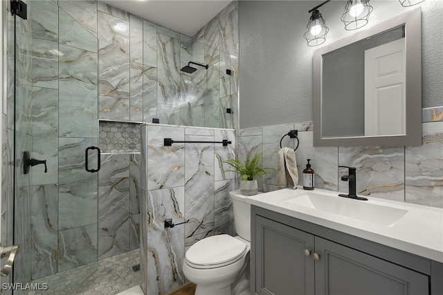 full bathroom featuring a textured wall, toilet, vanity, tile walls, and a shower stall