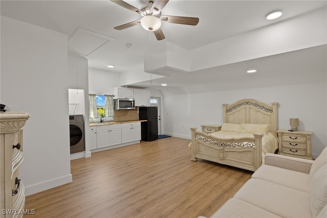 bedroom with freestanding refrigerator, light wood finished floors, washer / dryer, and baseboards