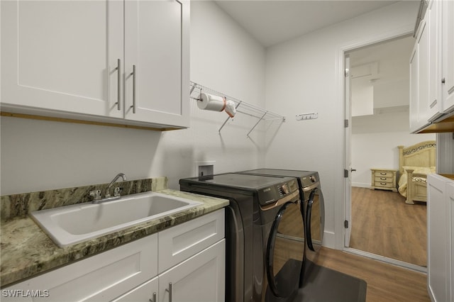 laundry area with sink, hardwood / wood-style flooring, washer and clothes dryer, and cabinets