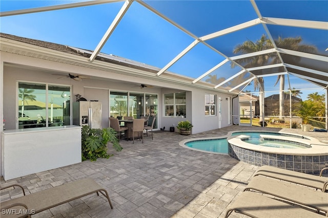 view of swimming pool with ceiling fan, a patio, glass enclosure, and an in ground hot tub