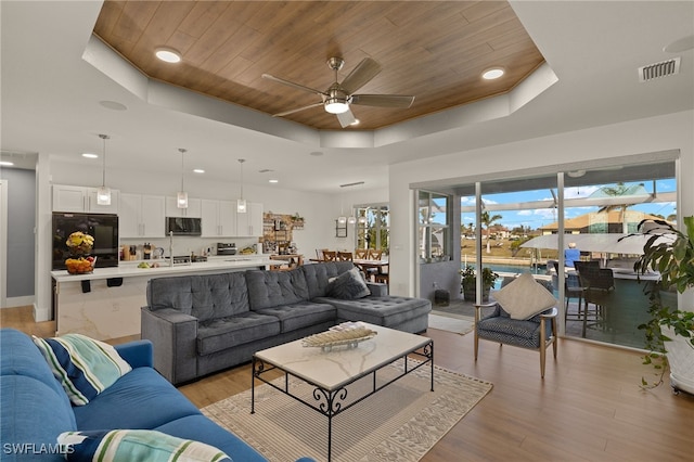 living room with a tray ceiling, wood ceiling, visible vents, and light wood-style flooring