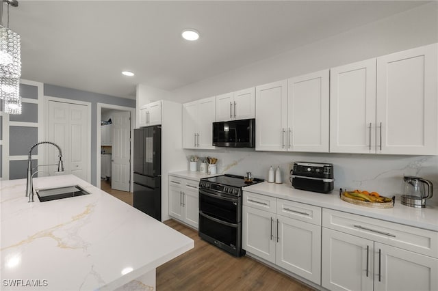 kitchen with white cabinetry, sink, range with two ovens, hanging light fixtures, and black fridge