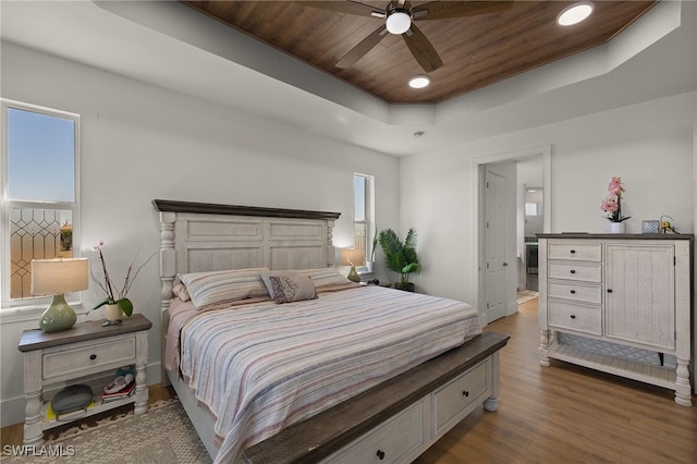 bedroom featuring ceiling fan, a tray ceiling, dark hardwood / wood-style flooring, and wooden ceiling