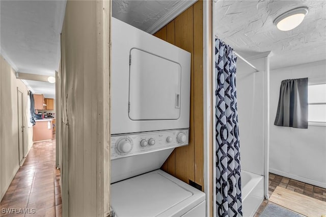 clothes washing area with stacked washing maching and dryer and light wood-type flooring