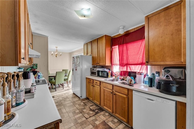 kitchen with sink, hanging light fixtures, white appliances, a notable chandelier, and a textured ceiling