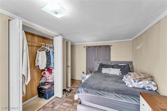 bedroom with a closet, crown molding, a textured ceiling, and wood walls