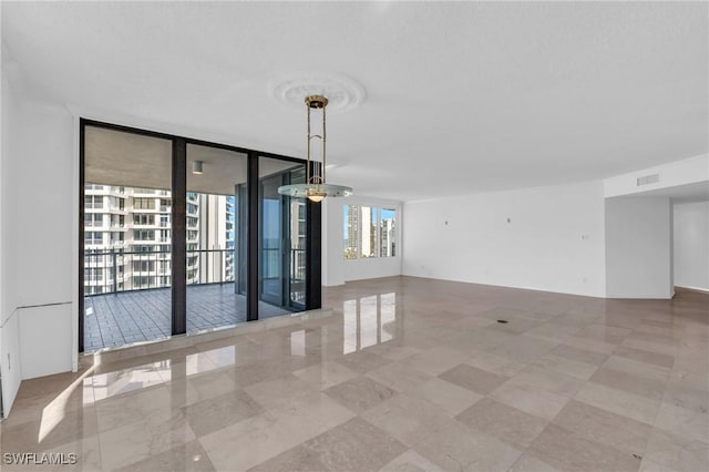 empty room with expansive windows and an inviting chandelier