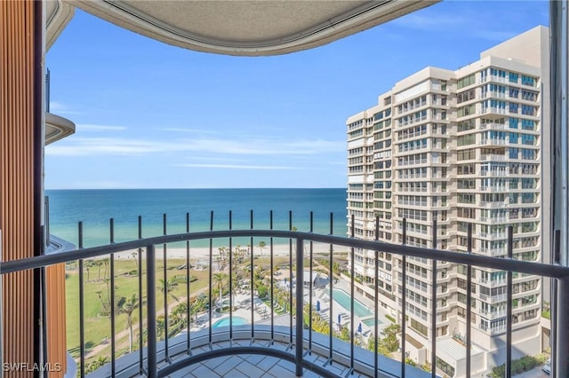 balcony with a water view and a view of the beach