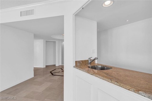 bar with white cabinetry, light stone countertops, and sink