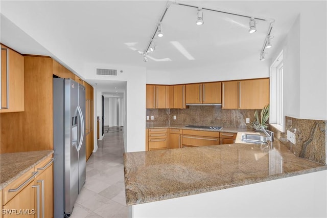 kitchen featuring light stone counters, stainless steel fridge with ice dispenser, sink, and kitchen peninsula