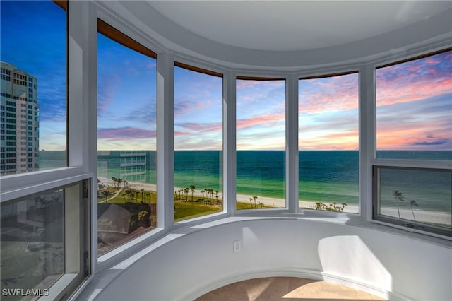 unfurnished sunroom featuring a water view and a beach view