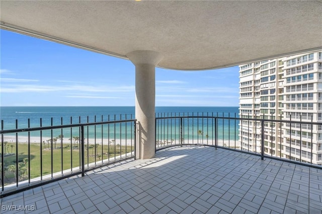 balcony featuring a view of the beach and a water view