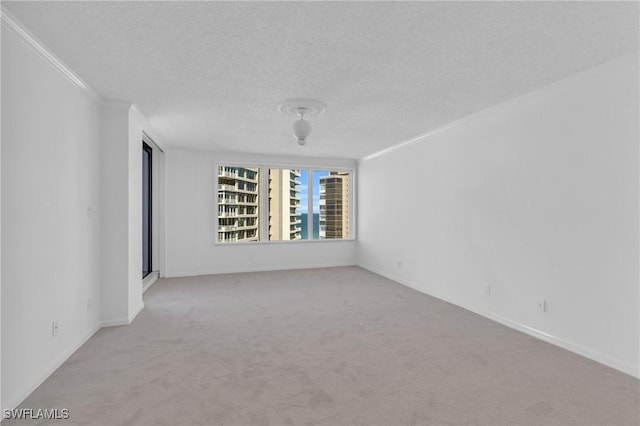 unfurnished room with ornamental molding, light colored carpet, and a textured ceiling