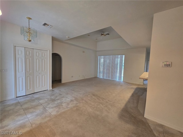 unfurnished living room featuring light carpet and an inviting chandelier