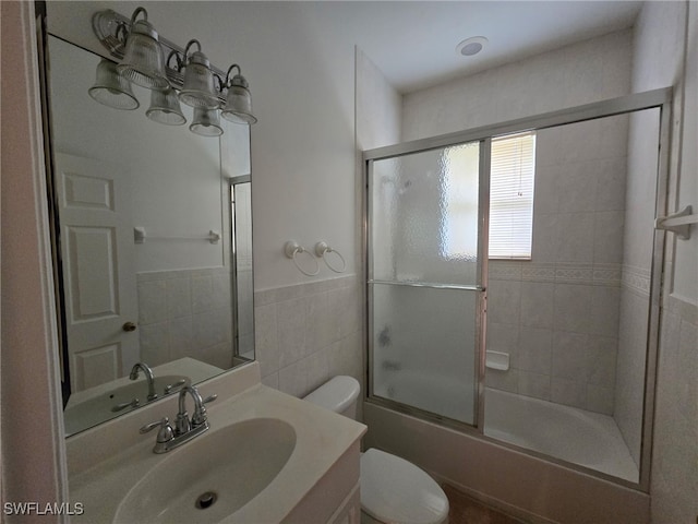 full bathroom featuring tile walls, vanity, shower / bath combination with glass door, and toilet