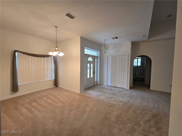 carpeted entryway featuring a healthy amount of sunlight and a notable chandelier