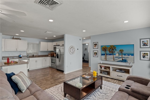 living room with hardwood / wood-style floors, sink, and ceiling fan