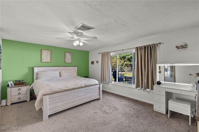 carpeted bedroom with ceiling fan and a textured ceiling