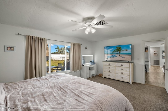 bedroom featuring ceiling fan, access to exterior, dark carpet, and a textured ceiling