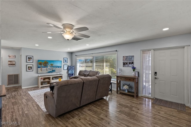 living room with ceiling fan, a textured ceiling, and dark hardwood / wood-style flooring