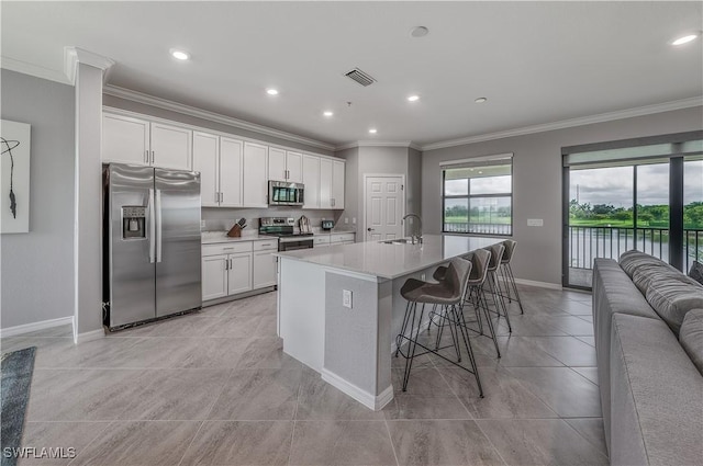 kitchen with visible vents, appliances with stainless steel finishes, ornamental molding, white cabinets, and a sink