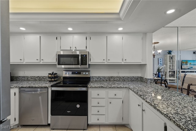 kitchen featuring dark stone countertops, stainless steel appliances, light tile patterned flooring, and white cabinets