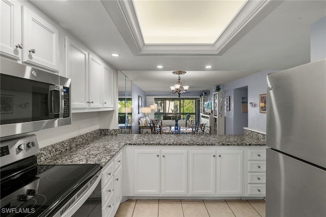 kitchen with a raised ceiling, white cabinetry, appliances with stainless steel finishes, and dark stone counters