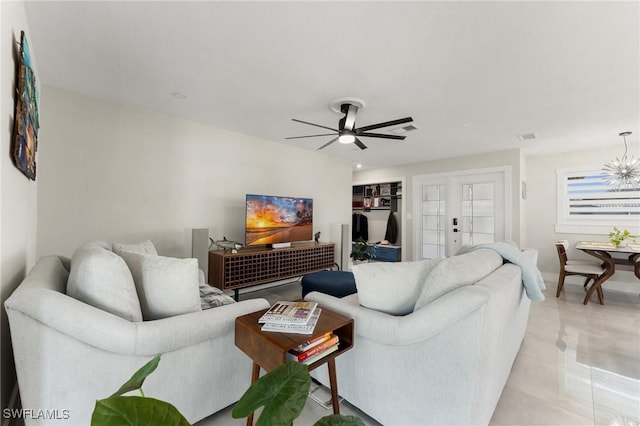 living room with light tile patterned flooring and ceiling fan with notable chandelier