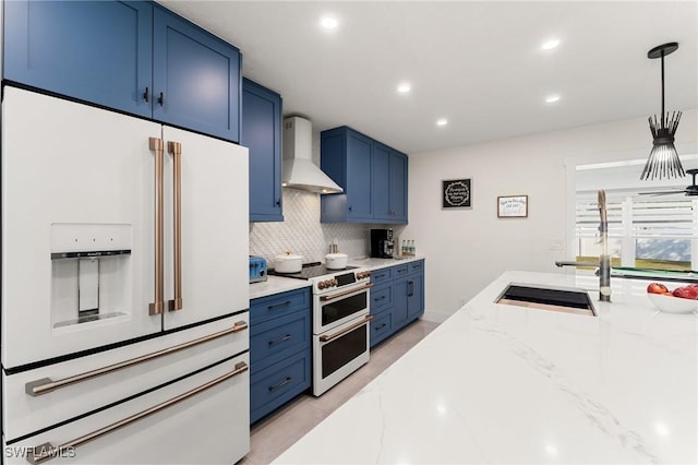 kitchen with wall chimney exhaust hood, blue cabinets, hanging light fixtures, white appliances, and backsplash