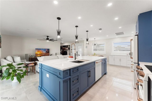 kitchen featuring blue cabinets, decorative light fixtures, a center island with sink, white dishwasher, and light stone countertops