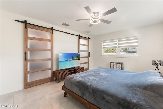 bedroom featuring ceiling fan, a barn door, and light tile patterned floors